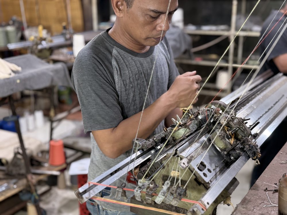 Artisan operating a manual knitting machine at Lualua